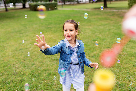 童,休闲人的快乐的小女孩玩肥皂泡夏季公园快乐的女孩公园玩肥皂泡图片