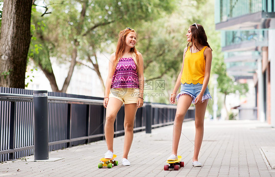 友谊,休闲人的快乐的十几岁的女孩朋友与短滑板城市街道夏天城市里短滑板的十几岁女孩图片