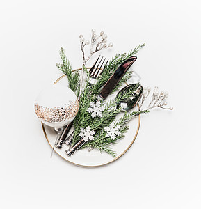 诞餐桌带冷杉树枝的盘子,餐具节日装饰白色背景上的球小雪花,顶部视图图片