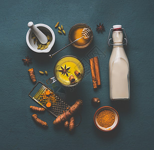 杯健康的金色姜黄香料牛奶,配料豆蔻,姜黄,肉桂,蜂蜜生姜灰色背景,顶部的视图免疫促进补救,排节食的图片