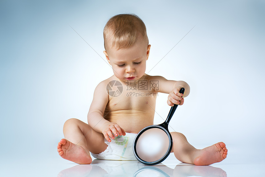 八个月的婴儿坐白色背景上玩放大镜图片