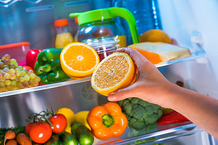 女人打开的冰箱里橘子健康的食物图片