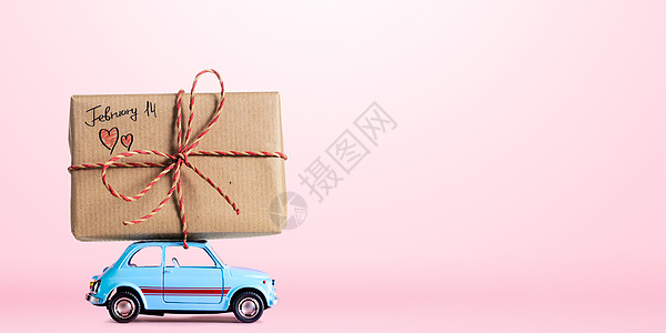 蓝色复古玩具汽车送礼品盒与2月14日的情人节标题粉红色背景图片