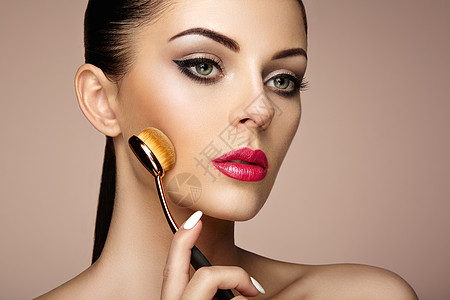化妆师用刷子涂斯金通漂亮的女人脸完美的妆容护肤基金会刷化妆师图片