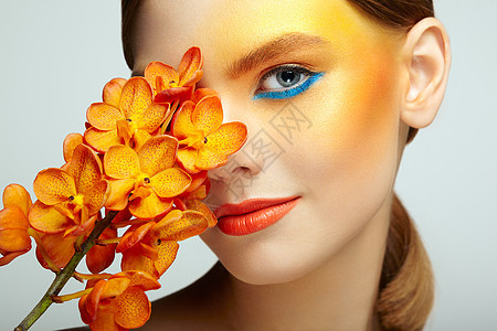美丽的轻女子兰花的肖像黑发女人,化妆豪华完美的皮肤睫毛化妆品眼影橙色的花背景图片