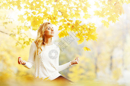 美丽的轻女子坐秋季公园的莲花瑜伽姿势秋天公园的瑜伽女人图片