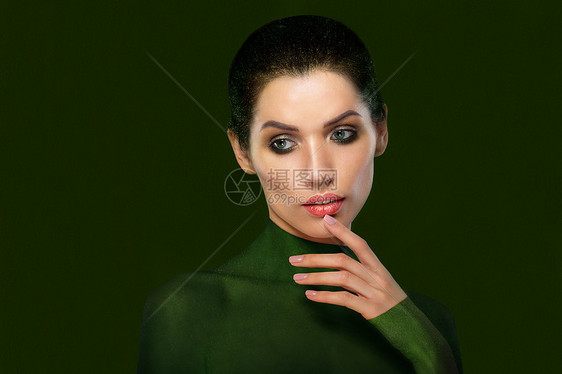 绿色背景上美丽女人的肖像特写脸想想吧拇指靠近嘴唇图片