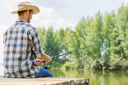 户外钓鱼夏天钓鱼戴帽子的轻人坐桥上钓鱼背景