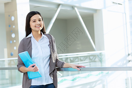 办公楼里魅力的女人轻的黑发女人现代璃内部与文件夹手图片