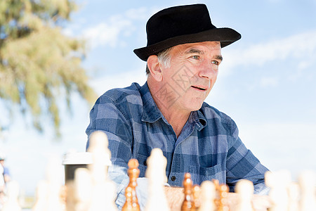 老人坐户外下棋思考国际象棋策略高清图片