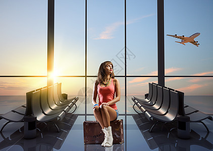 暑假旅行轻漂亮的女孩旅行者机场坐手提箱上图片