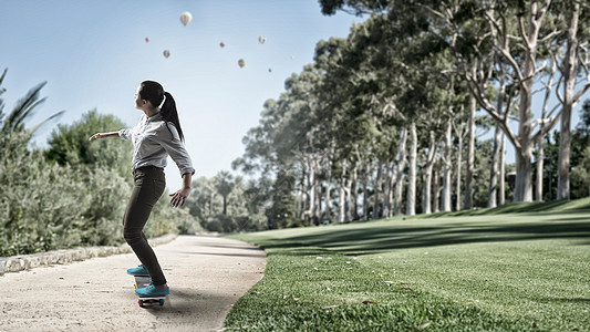 女孩骑滑板活跃的女孩公园的路上骑滑板图片