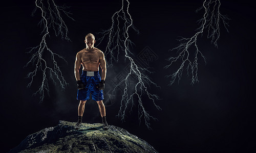 箱式战斗机户外训练黑暗背景下的强壮拳击手展示了力量耐力图片