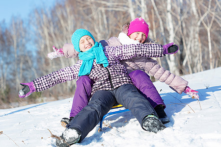 孩子冬天的乐趣两个可爱的女孩美丽的雪冬公园里享受雪橇背景