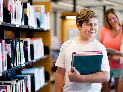 图书馆里的男孩选择书图书馆里的男孩背景图片