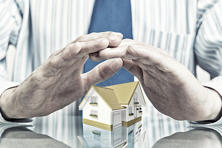 房地产保险商人的手,小心翼翼地盖住房子的模型图片