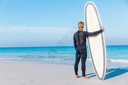 个轻的冲浪者海滩上冲浪等待个完美的波图片