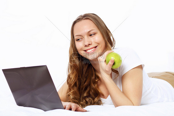 微笑的女人拿着苹果看着电脑图片
