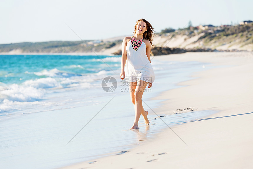 轻的女人沿着海滩散步沿着沙滩散步的轻漂亮女人的肖像图片