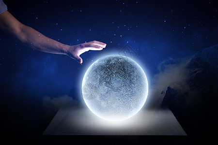 蓝色的月亮靠近人的手触摸蓝色发光的月亮图片