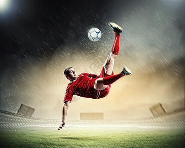 足球运动员击球足球运动员穿着红色衬衫雨中体育场击球图片