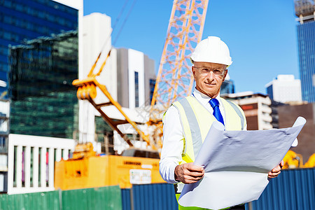 建筑工地的工程师建设者工程师建筑工人施工场景穿着带蓝图的安全背心背景图片