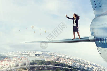 高空中飞机机翼上的女人女商人站飞机机翼上自拍图片