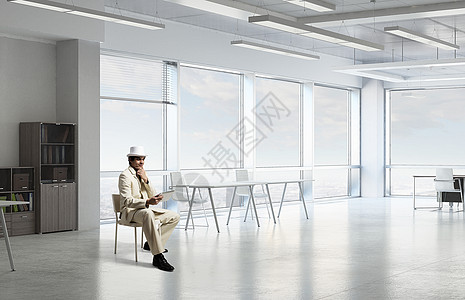 优雅的商人用平板电脑穿着白色西装的英俊轻商人坐办公椅上用平板电脑图片