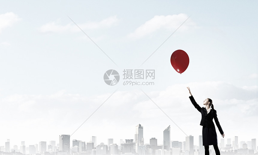 气球的女人轻的女商人伸手触摸天空中的气球