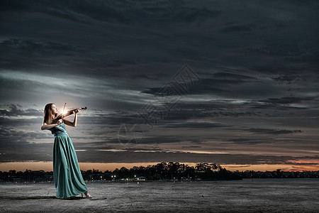 穿着绿色长裙的迷人女人拉小提琴优雅的小提琴演奏家图片