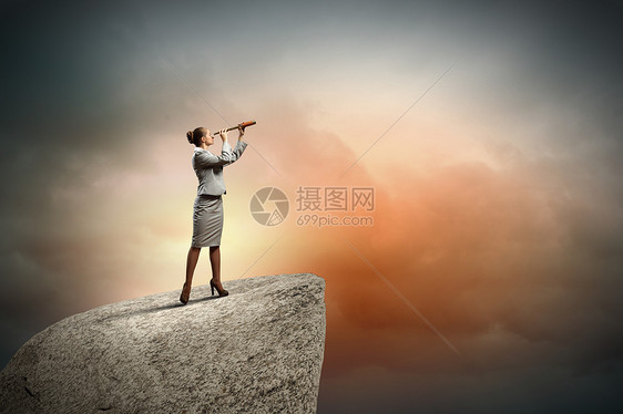 望远镜的商业女人女商人站岩石顶上用望远镜看的形象图片