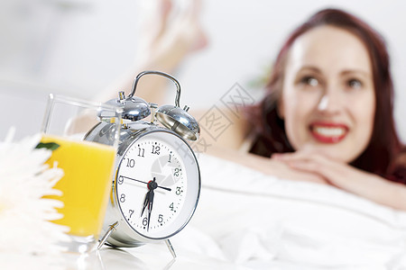 轻快乐的女人躺床上微笑早上好图片