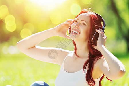 大自然的声音轻漂亮的女人夏天的公园里用耳机享受音乐图片
