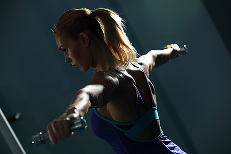 肩部锻炼健身女孩健身房锻炼哑铃的形象图片
