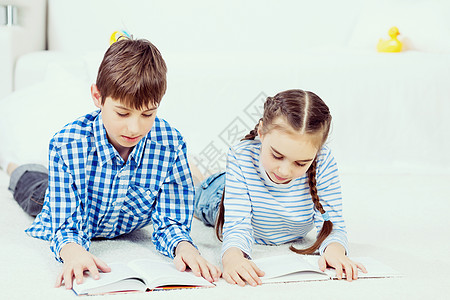 可爱的孩子看书学校男孩女孩躺地板上看书图片