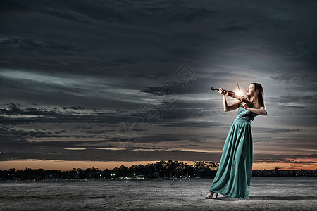 穿着绿色长裙的迷人女人拉小提琴优雅的小提琴演奏家图片