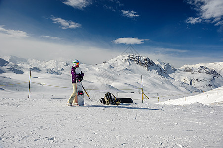 轻的女人,滑雪板户外滑雪护目镜与法国阿尔卑斯山覆盖雪的背景瓦尔迪塞尔,法国图片