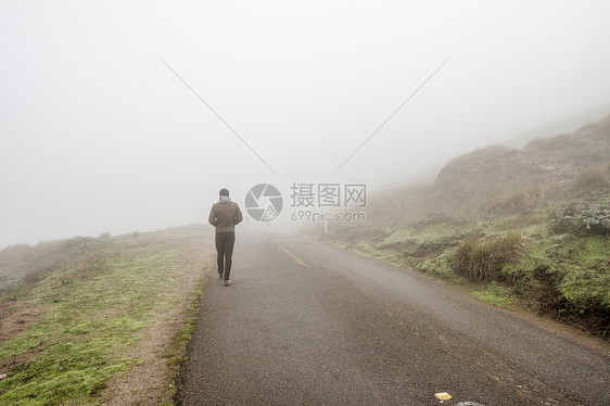 孤独的人穿过白雾沿着路走图片