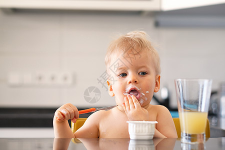 可爱的岁小男孩用勺子吃酸奶蹒跚学步的孩子肮脏凌乱的脸图片