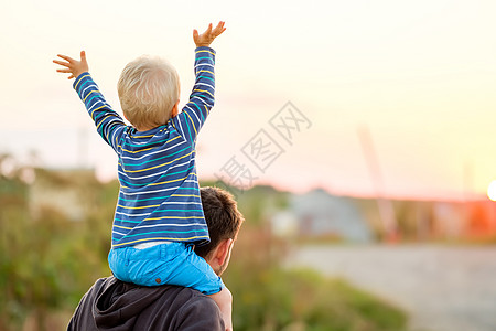 小孩背快乐的男人他的孩子户外玩得很开心家庭生活方式农村场景的父亲儿子夕阳的阳光下背景