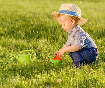 小孩背影户外幼儿的肖像农村场景岁小男孩戴草帽用浇水罐背景