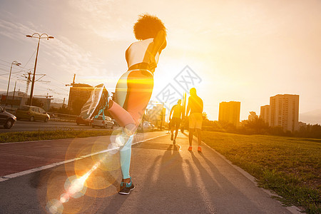 轻的黑人女孩慢跑美丽的早晨,太阳升城市的街道上图片