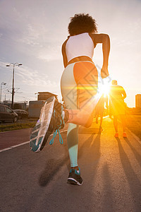 轻的黑人女孩慢跑美丽的早晨,太阳升城市的街道上图片