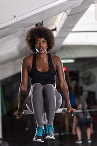 非裔美国运动员妇女水平双杠上锻炼手臂,锻炼三头肌头肌,俯卧撑图片