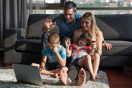 快乐的轻家庭玩笔记本电脑家坐沙发上图片