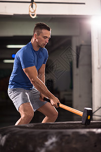 大锤轮胎用拖拉机轮胎健身房锻炼轻的肌肉男图片