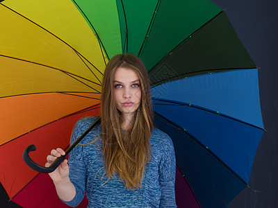 位轻英俊的女人的肖像,她带着把五颜六色的雨伞,孤立灰色的背景上图片