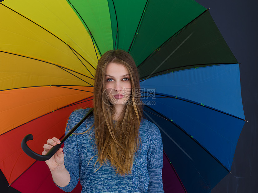 位轻英俊的女人的肖像,她带着把五颜六色的雨伞,孤立灰色的背景上图片