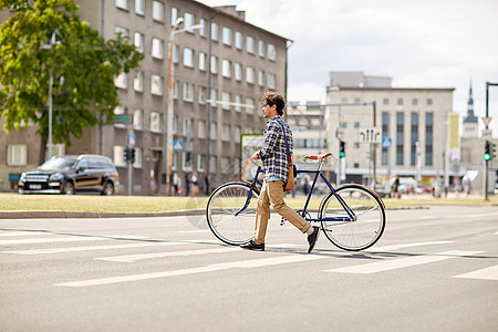 人,风格,城市生活生活方式轻的时尚男子肩袋固定齿轮自行车穿越人行横道街上图片