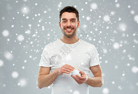 美丽,护肤,冬天,诞节人们的微笑的轻人与奶油罐雪上的灰色背景图片